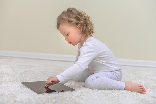 Little girl draws or plays on the tablet computer. Children and gadgets.