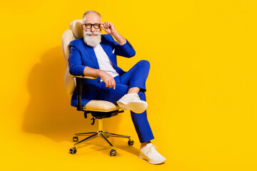 Fototapeta na wymiar Full length body size photo of man with white beard smiling sitting inoffice chair isolated vivid yellow color background