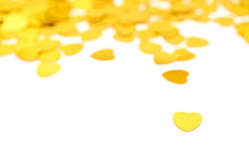 Gold color confetti on a white isolated background. Love and romance abstract background. Saint Valentine theme. Copy space, selective focus