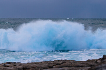 Big wave breaking into water spray on the coast.