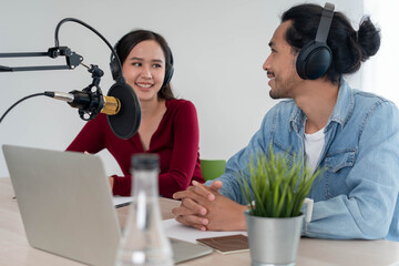 Asian record radio presenter Podcast in the studio. A male and female speaker talks live via the...