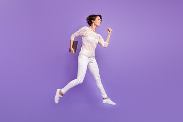 Fototapeta na wymiar Full length photo of charming young lady dressed white shirt jumping holding modern device isolated purple color background