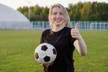 Young teen girl football player holding soccer ball with thumb up