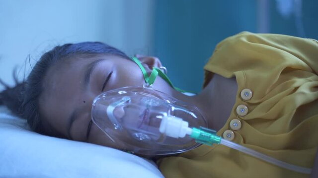 Little Girl kid breathing on ventilator oxygen mask due to coronavirus covid-19 breathing shortness or dyspnea infection -concept of children Healthcare and medical during third wave pandemic outbreak