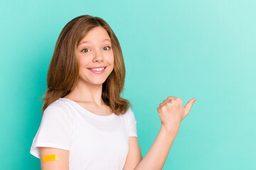 Photo portrait girl got vaccine from covid-19 pointing blank space thumb isolated vibrant teal...