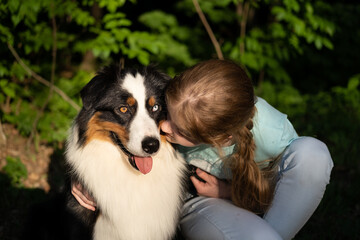  teenage girl kiss australian shepherd dog in summer. in forest