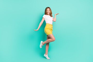 Fototapeta na wymiar Full length body size photo smiling schoolgirl keeping copyspace on hand isolated vivid teal color background