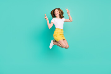 Fototapeta na wymiar Full length body size photo smiling schoolgirl jumping up showing v-sign isolated vivid teal color background