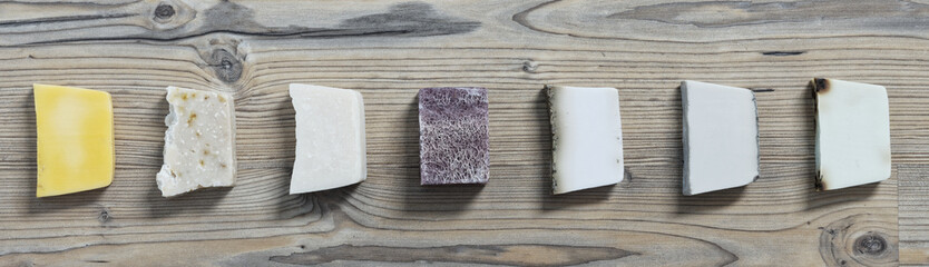 Natural colorful soaps in row flat lay, top view. Wooden table.