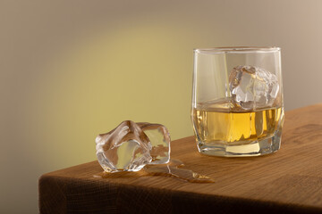 Whiskey or alcoholic beverage, with ie in a square formed designer glass. Sitting on an Oak table,...