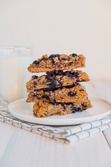 Stack of homemade oatmeal scones with berries stacked on white plate and glass of plant based milk. Vegan sweet baked food. Gluten free pastry. Healthy breakfast.