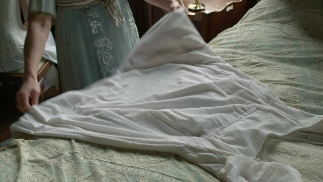 Woman in period costume with white skirt on bed, Leicester, Leicestershire, UK