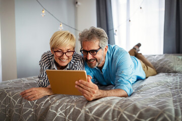 Happy smiling mature couple using digital tablet at home