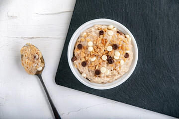Sweet appetizing banana porridge with nuts and pieces of chocolate 