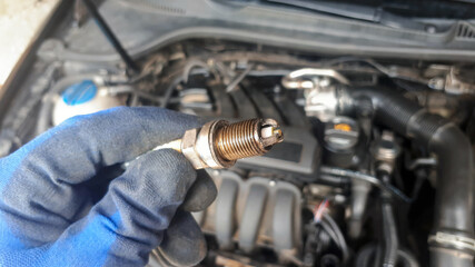 Old dirty car candle on engine background in human hand. Mechanic concept. repair