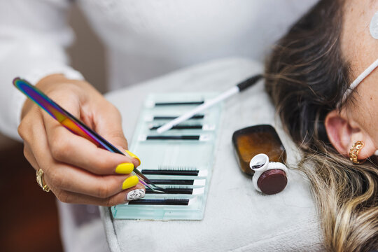 Crop beautician with client and fake eyelashes in salon