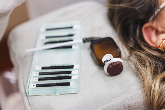 Crop beautician with client and fake eyelashes in salon
