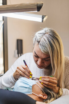 Beautician applying eyelashes on face of woman