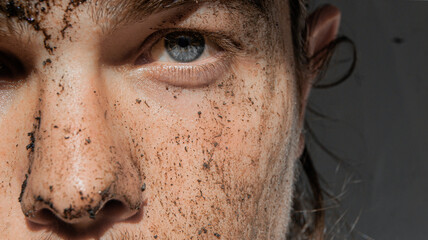 man with mud on his face. He looks with his colored eye. white background.
