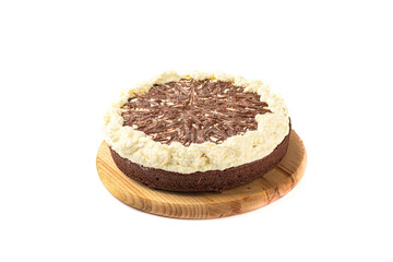 Chocolate cream cake garnished with whipped cream on a cutting board over a white background.
