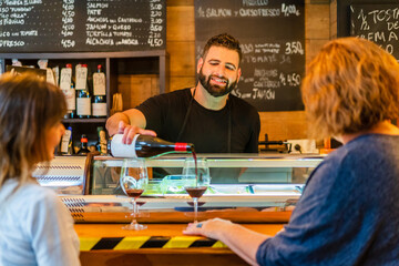 Barman pouring red wine in cafe