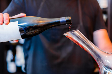 Barman pouring red wine into decanter