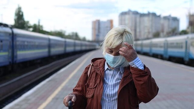 Portrait of senior woman wearing protective face mask outdoors at the train station