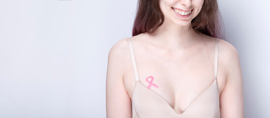 World Breast cancer day concept. Woman in bra with pink ribbon painted on her chest. October Breast Cancer Awareness month. Copy space