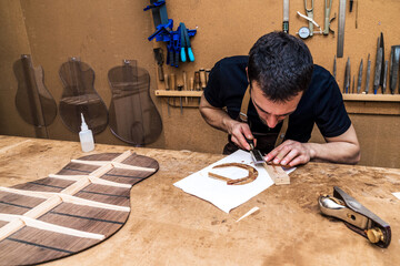 Craftsman cutting wooden block with file in workshop