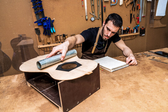 Luthier examining guitar sound board in workshop