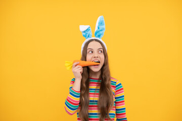 amazed easter teen girl in rabbit bunny ears eating carrot for holiday, easter holiday