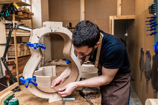 Luthier building guitar at table in workshop
