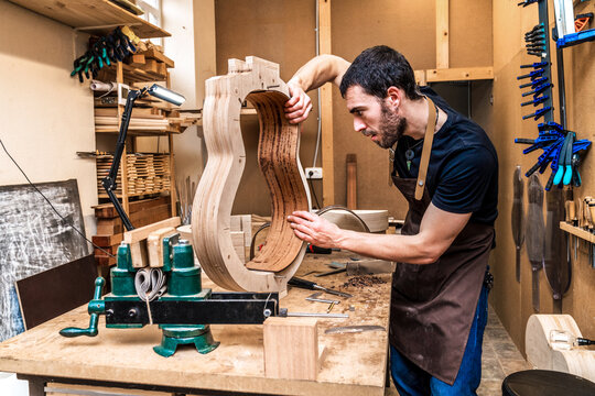 Luthier building guitar at table in workshop
