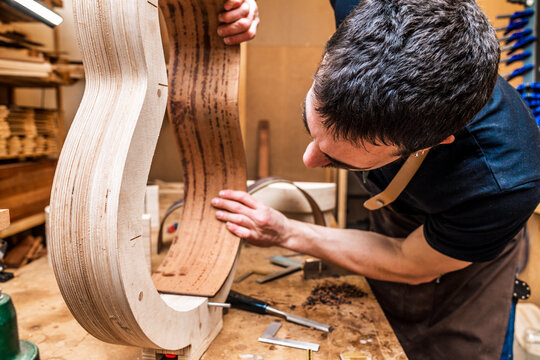 Luthier building guitar at table in workshop