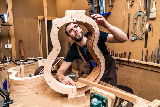 Luthier building guitar at table in workshop