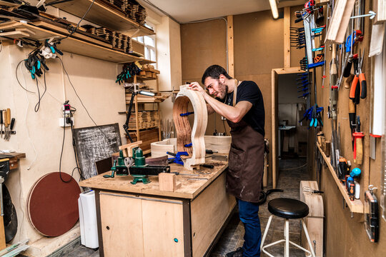 Luthier building guitar at table in workshop