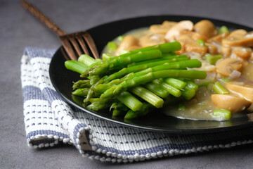 Asparagus green, and mushroom on plate on black background 