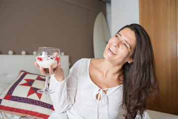 Attractive middle-aged brunette Spanish woman posing with a glass of ice cream with fruits