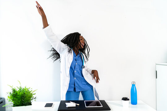 Black female doctor in medical uniform dancing in clinic