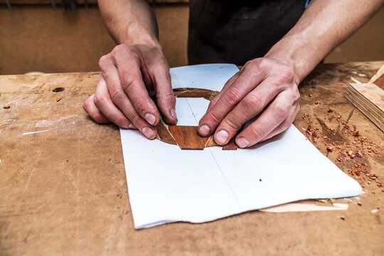 Faceless craftsman putting wooden pieces on paper in workshop