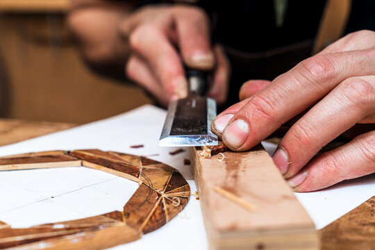 Crop craftsman cutting wooden block with file in workshop