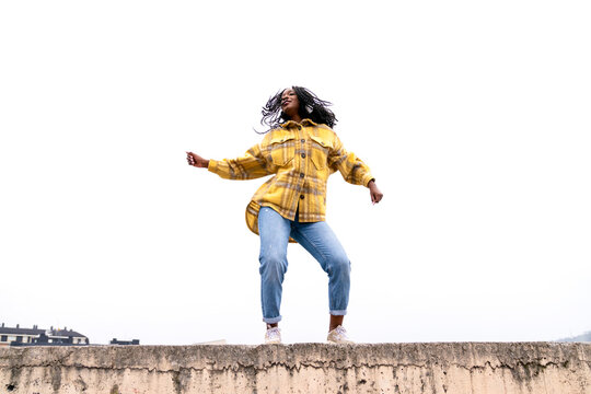 Energetic black woman dancing on concrete border