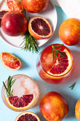 Blood orange cocktails with fresh fruits on blue table background. Summer cocktails, lemonade, refreshing drinks, low alcohol mocktail, party concept. Flat lay, top view.