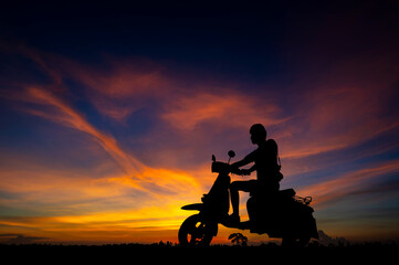 Silhouette man sitting on motorcycle  with colorful sunset background.Black motorcycle scooter in vivid sunrise purple sky.