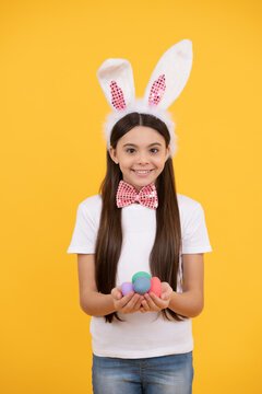 happy easter kid girl in bunny ears and bow tie hold painted eggs, egg hunt