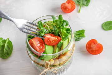 Healthy homemade salad in glass jar with quinoa, vegetables and herbs om white background. Vegan food concept.