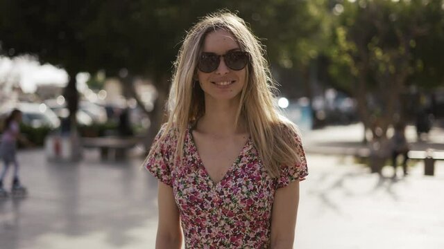 Camera follows young blondy woman in dress in sunny summer day