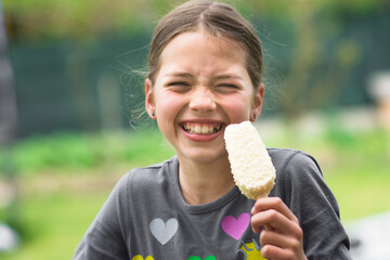 Child eating ice cream and make grimace. Holiday and summer concept.