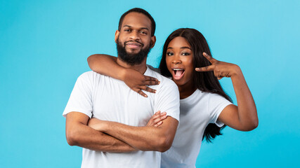 Black couple posing showing victory sign or peace gesture