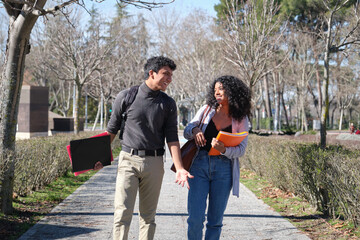Two latin students talking and smiling at the college campus. University life.